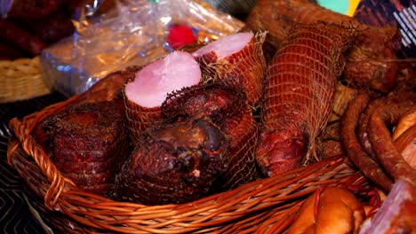 embutidos, jamón y tocino ahumado - productos caseros, en una canasta de mimbre en un mercado