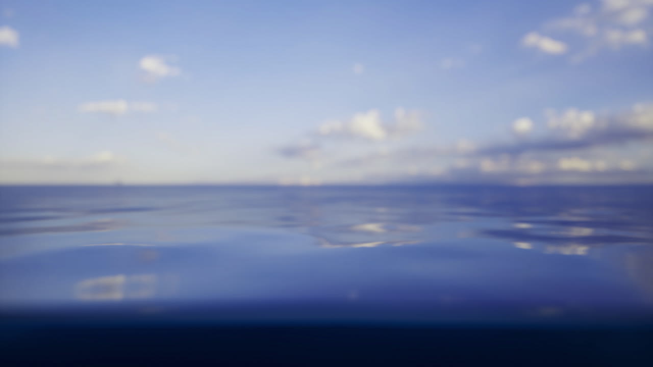 Calm ocean waters under a clear blue sky with scattered clouds at sunset