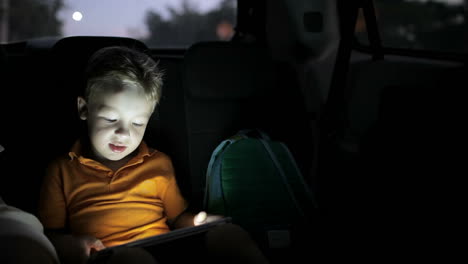 Niño-Usando-Tablet-Pc-Durante-El-Viaje-En-Automóvil-Por-La-Noche