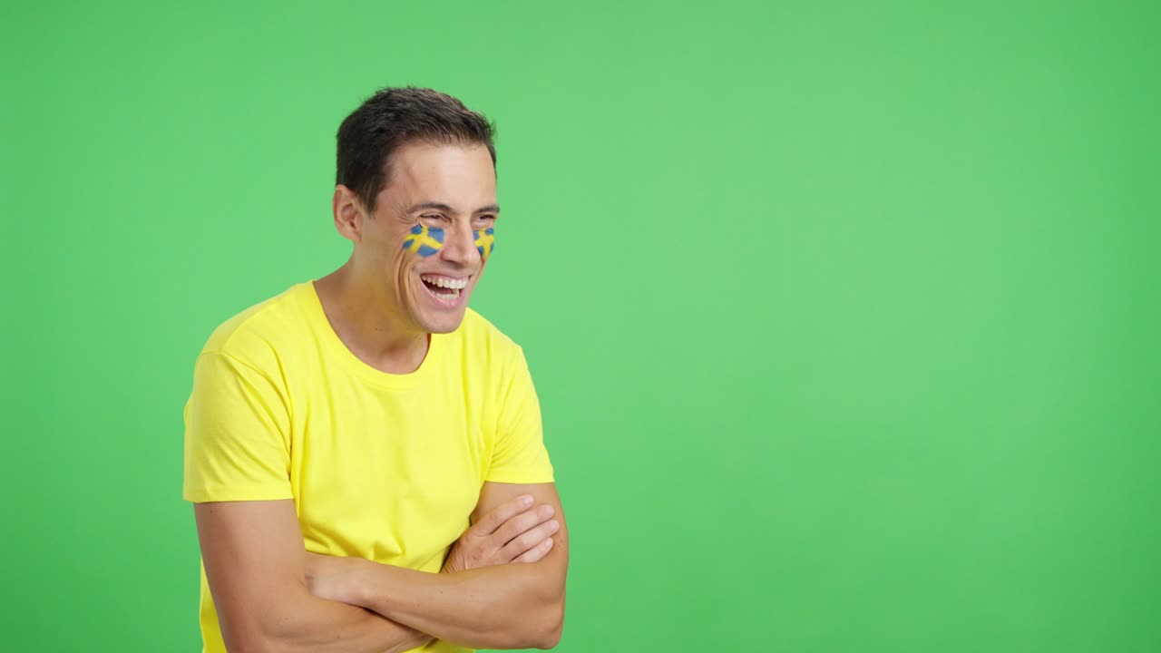 Happy man with swedish flag painted on face looking away