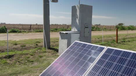 Tilt-up-view-of-solar-panels,-a-transformer,-and-a-power-post-in-the-countryside