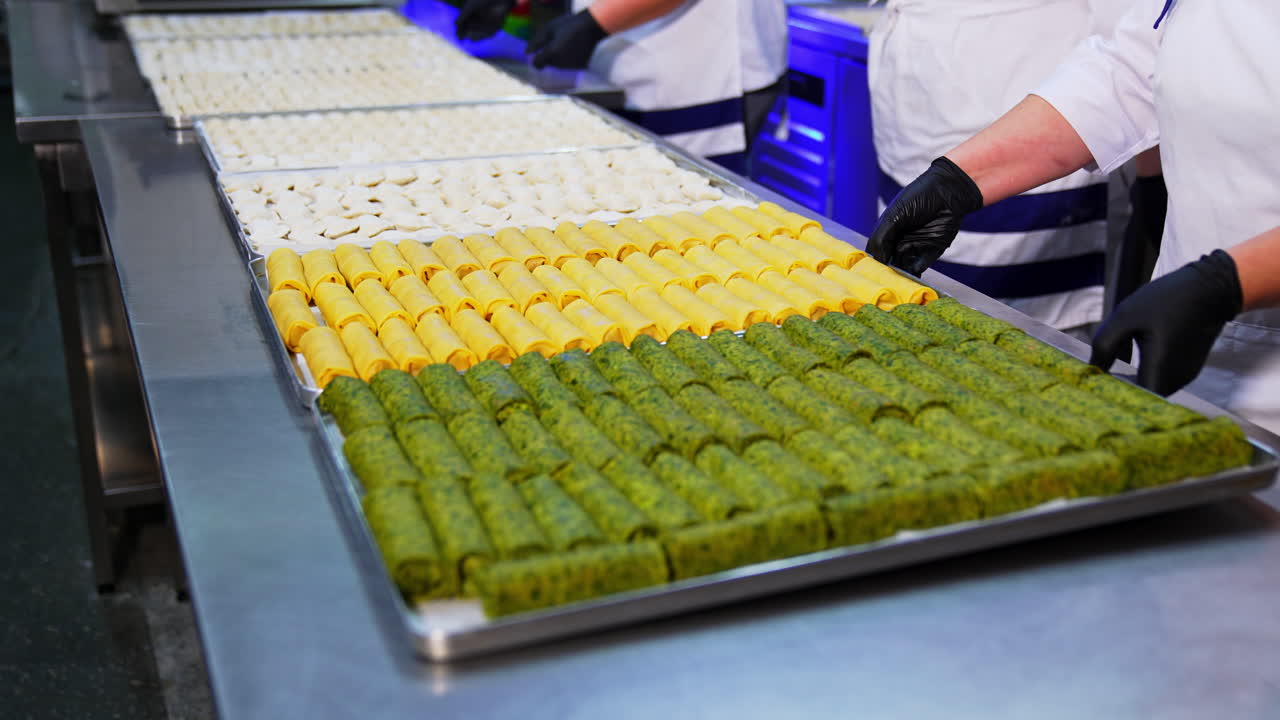 Cooks in white outfit put the metal trays with prepared food on the table. Beautifully laid crepes and ravioli at restaurant.
