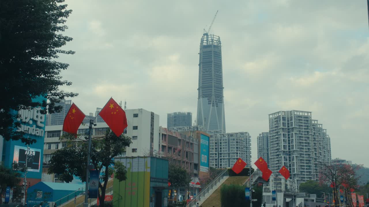 Skyline di Shenzhen con grattacielo in costruzione, bandiere cinesi e vista a livello stradale.