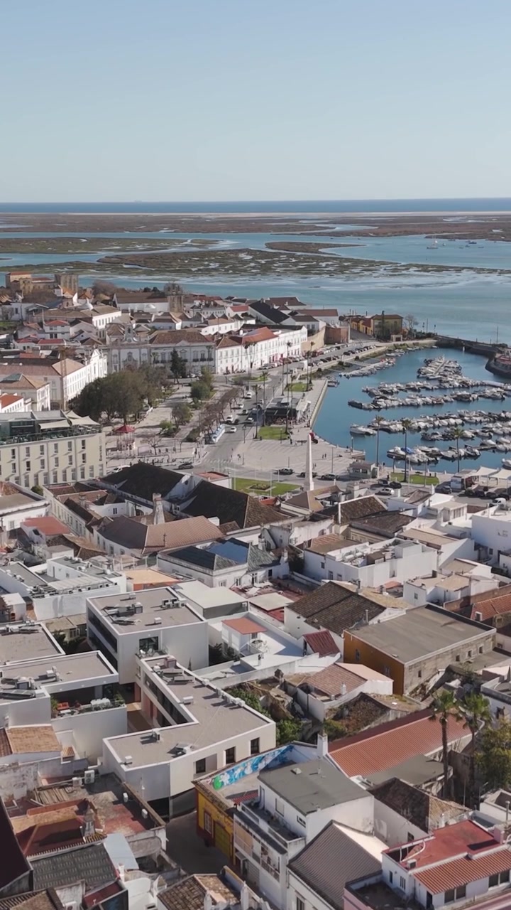 Smooth vertical aerial flight over Faro, revealing the historic old town, traditional buildings, and harbor ahead.