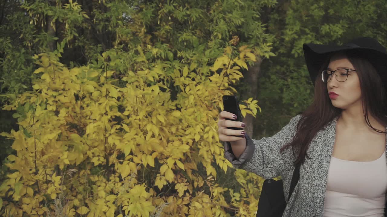 женщина делает селфи в осеннем парке.