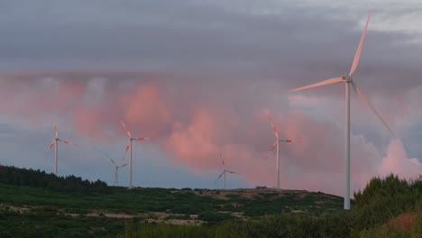 wind turbines spinning on mountain plateau with dramatic clouds in background