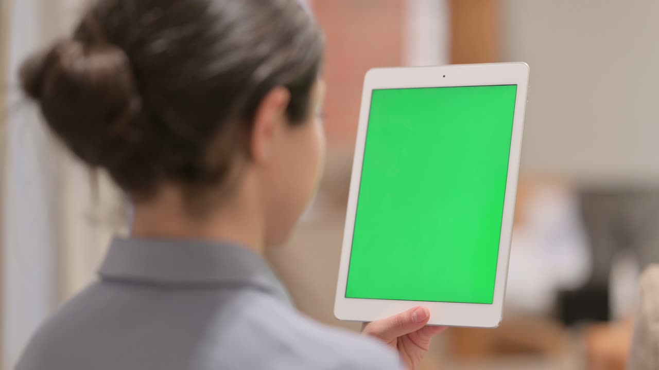 vista trasera de una joven india usando una tableta con pantalla cromada