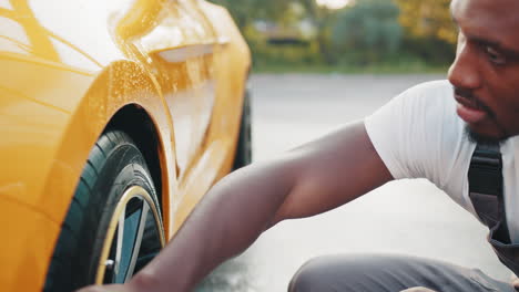 man washing a yellow car