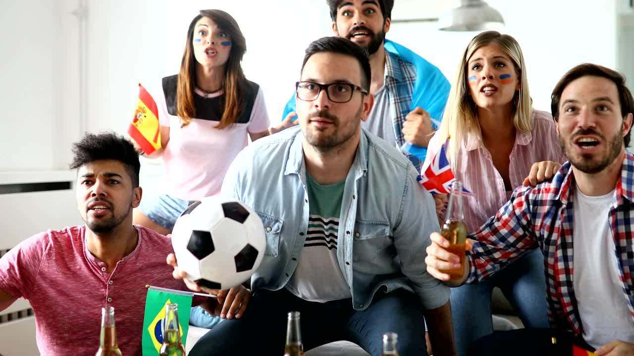 Friends or football fans watching soccer on tv and celebrating victory at home.