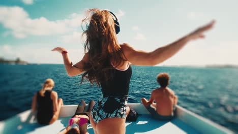 happy woman dances on the roof of a moving boat in headphones