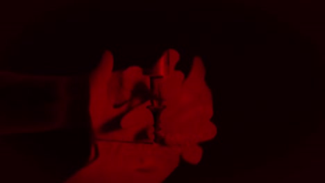 manos femeninas unidas con luz roja sobre fondo negro