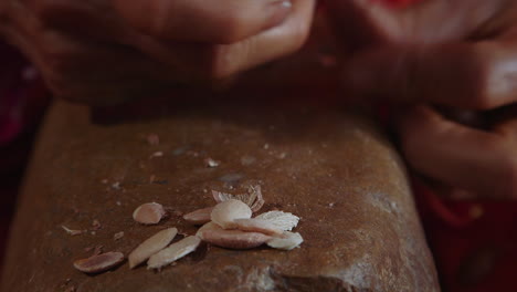 Close-up:-Old-woman's-hands-crushing-Argan-nuts-with-rock,-Shallow-DOF