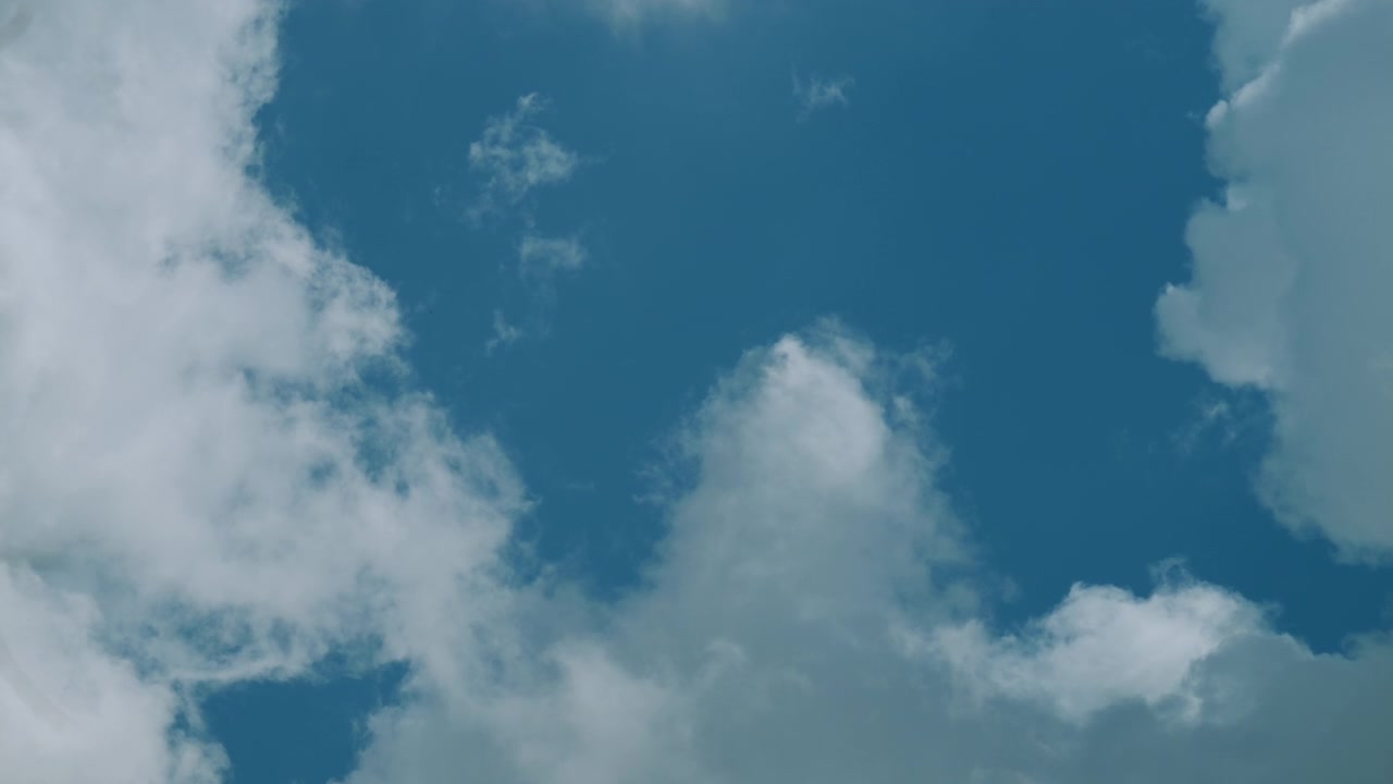 Soft white clouds drift slowly across a bright blue sky, creating a peaceful natural background