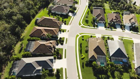 Aerial-of-a-sunny-suburban-neighborhood-going-down-the-street-with-bird-flying-by