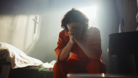 inmate praying deeply to god in sunlit prison cell