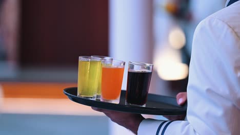 un camarero sostiene una bandeja de diferentes refrescos en vasos durante un evento