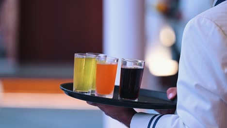 a waiter holds a tray of different soft drinks in glasses during an event