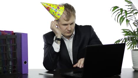 drank sleepy young businessman with hangover in festive cap falling asleep