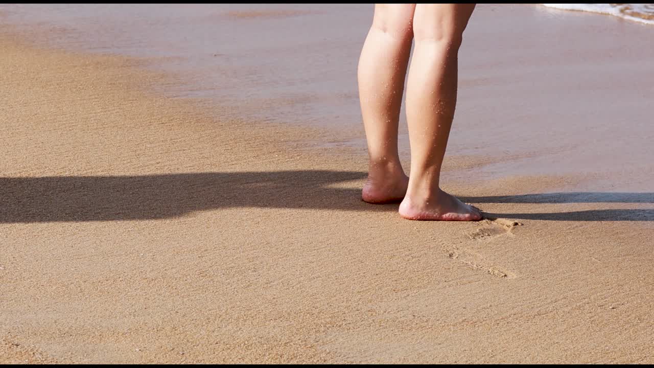 A person walks barefoot along a sunny beach in Phuket, Thailand, capturing the serene and relaxed atmosphere