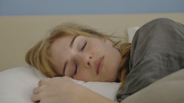 Eine Frau, die einschläft, die Person legt sich auf ein Kissen auf ihrem Bett – ruhige Aufnahme