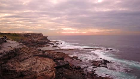 Toma-Aérea-Del-Amanecer-De-Terciopelo-En-La-Playa-En-Una-Mañana-Nublada-Y-Ventosa