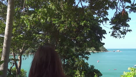 asian girl descends the stairs with greenery around and with a view to the sea