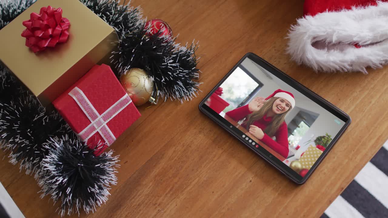 mujer caucásica sonriente con sombrero de santa en una videollamada de navidad en una tableta