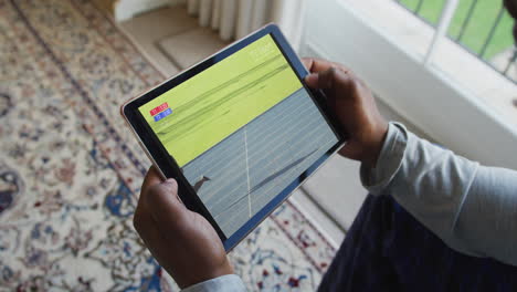 composite of man sitting at home, watching athletics running event on tablet