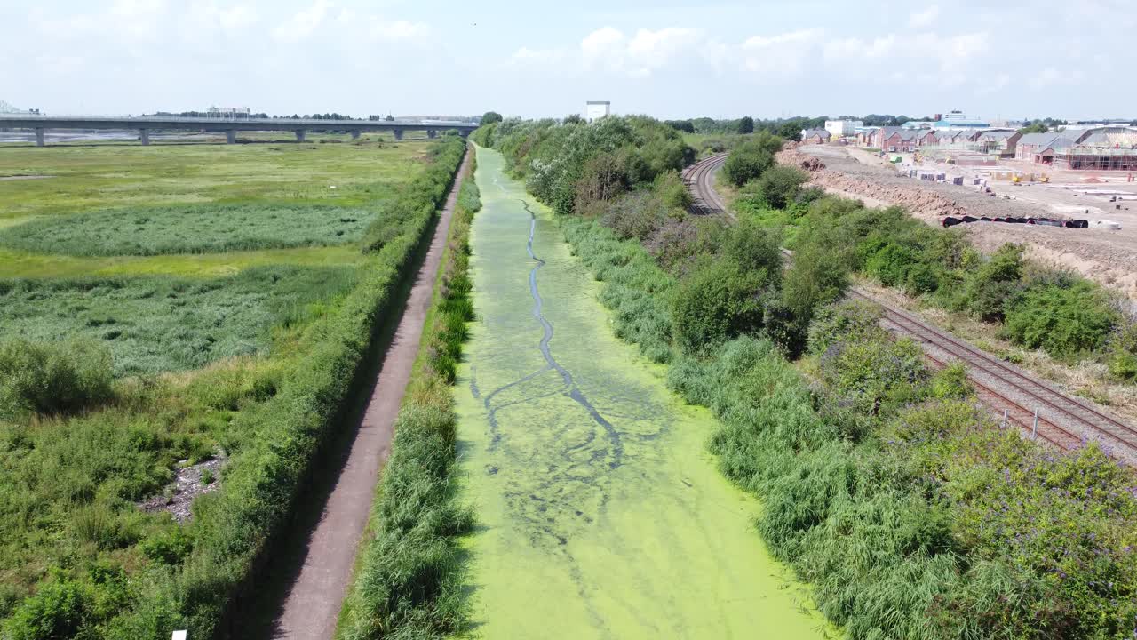 canal de campo cubierto de algas verdes junto con nueva construcción de viviendas sitio vista aérea tiro ascendente