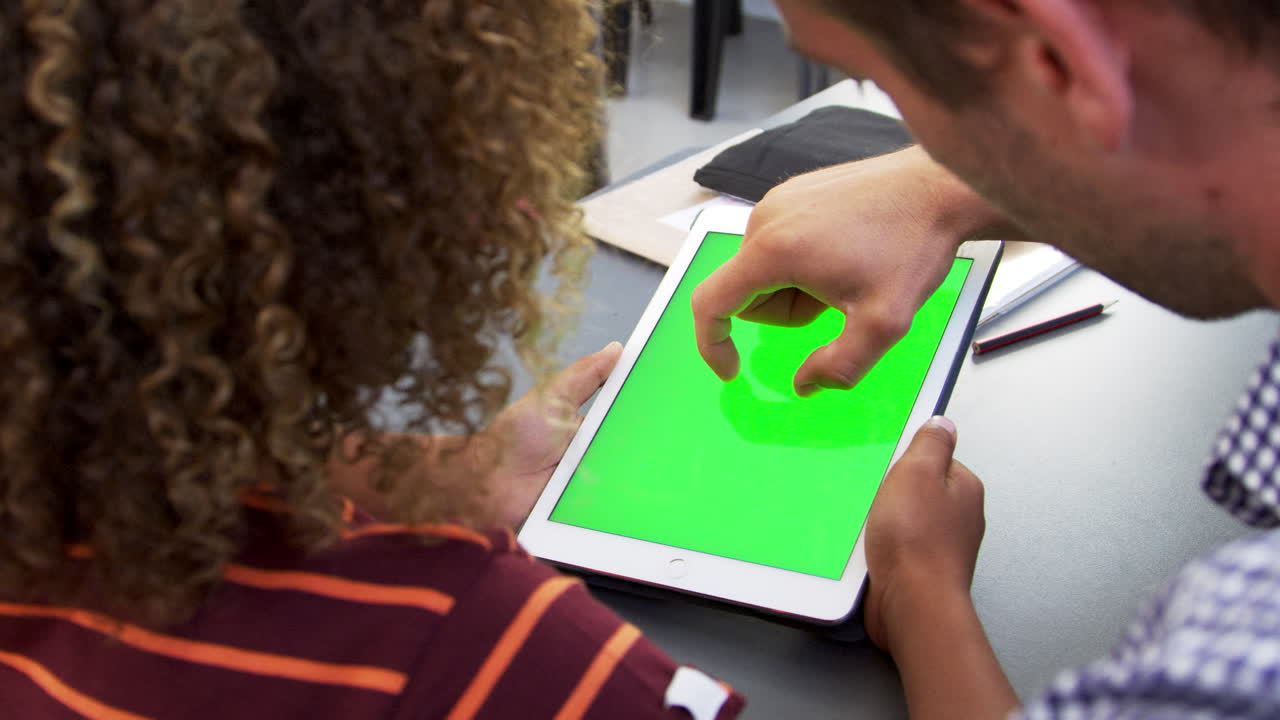 maestro y un joven escolar usando una tableta en clase