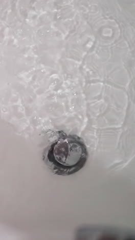 woman stands in bathtub with dripping water closeup. lady foot in clear liquid and falling shower drops in bathroom. woman enjoys cozy bath