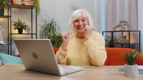 Überglückliche-ältere-Frau,-Die-Am-Laptop-Arbeitet,-Feiert-Erfolg,-Gewinnt-Geld-In-Der-Lotterie-Und-Erhält-Online-Gute-Nachrichten