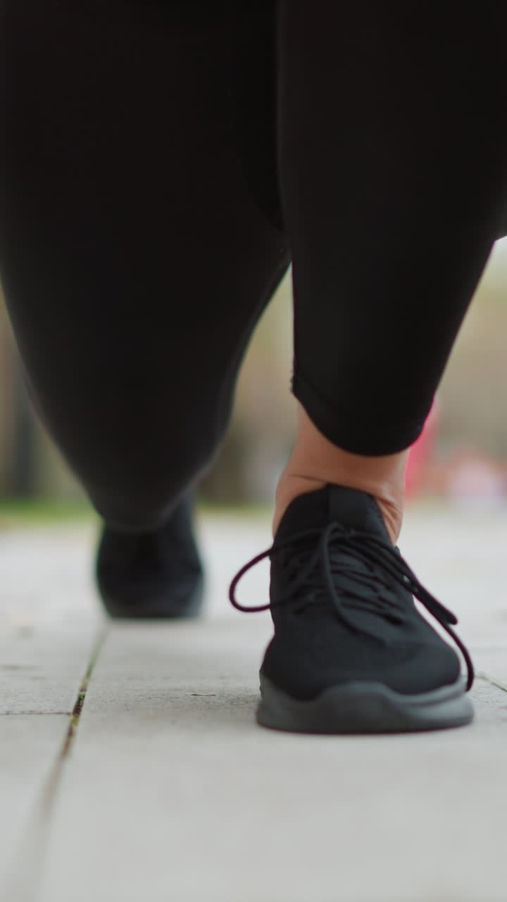 Close view of lady s leg in black sneakers set on ground, ready to run with hands down in a game park, focused athletic action shot in a park setting, preparing for a run or exercise session