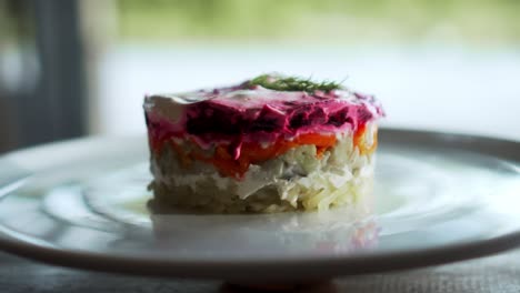 traditional russian salad with beetroot and herring vegetables, lying on a wooden table in a white plate