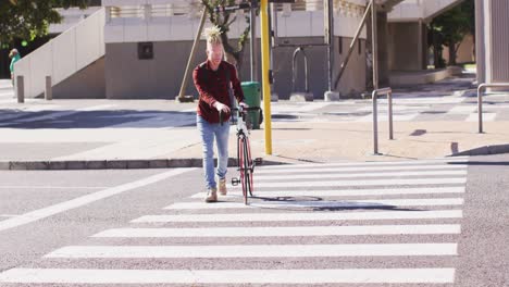 Albino-african-american-man-with-dreadlocks-crossing-road-with-bike