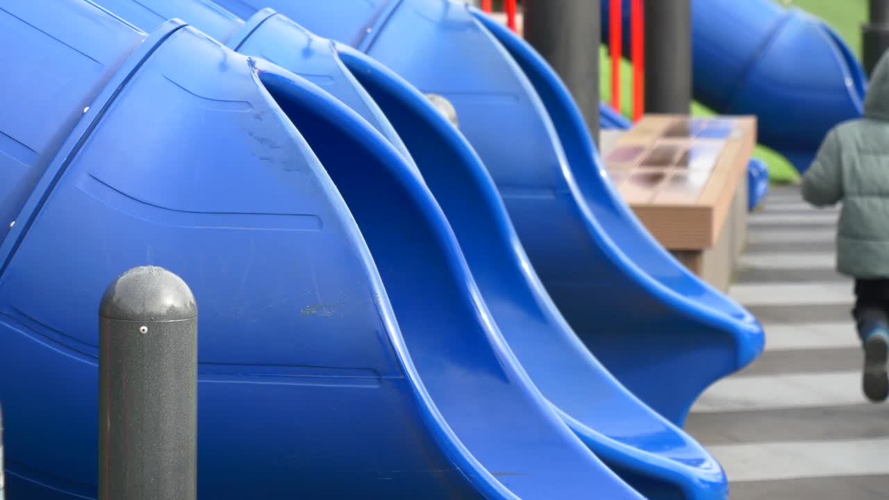 un niño en un patio de recreo con toboganes azules