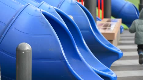 a child on a playground with blue slides