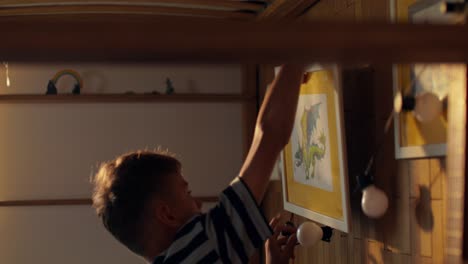 child hanging pictures on the wall