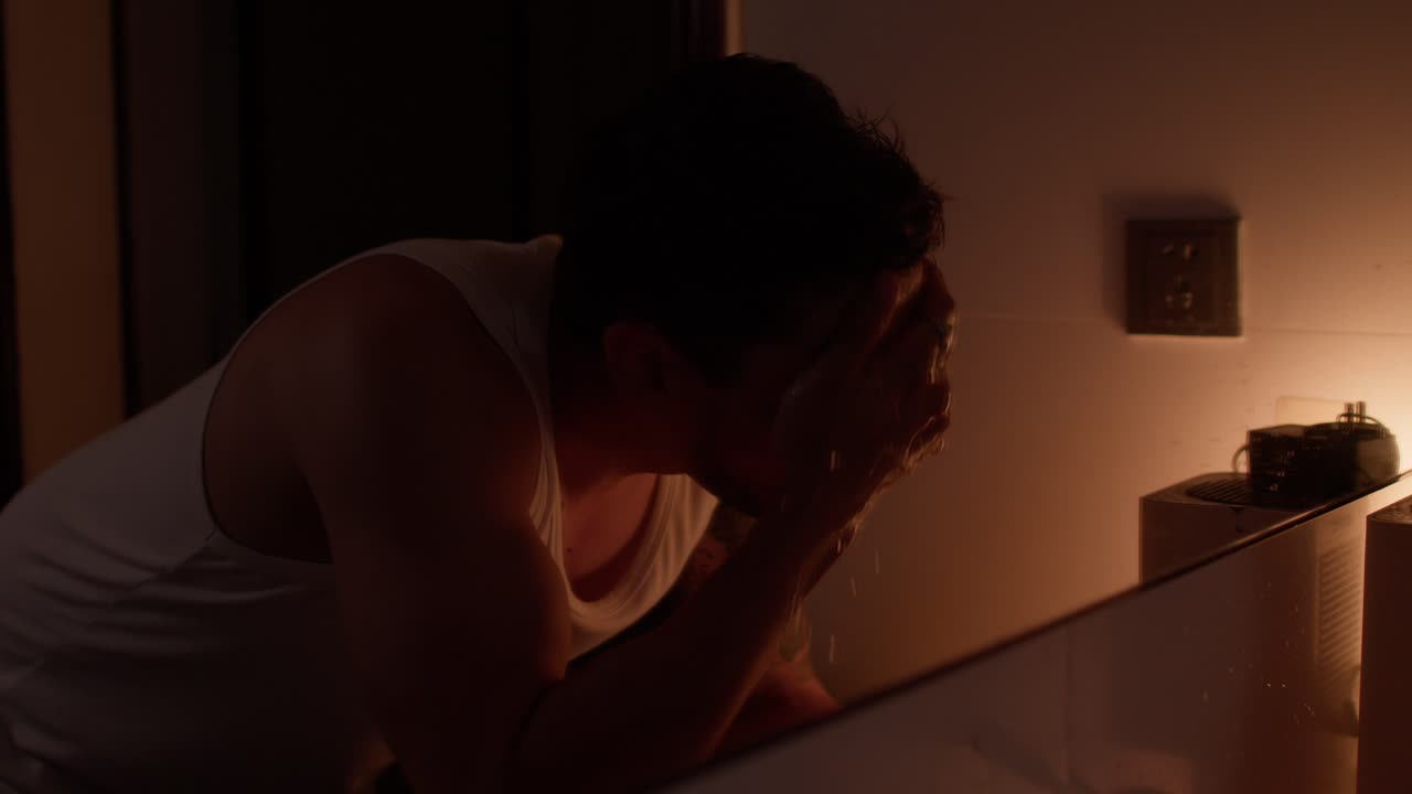 Man in bathroom washing face