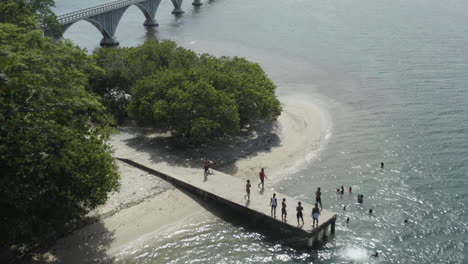 AERIAL---Bridge-and-people-on-small-dock,-Samana,-Dominican-Republic,-forward-tilt-up