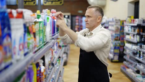 A-middle-aged-store-worker-arranges-goods-on-a-shelf.-Work-in-the-store.-Control-the-product.-Happiness