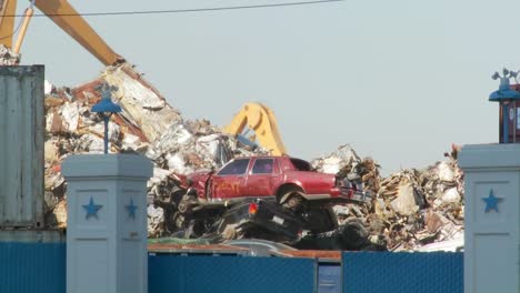 cranes lift and move scrap metal around abandoned and destroyed cars in a junkyard or scrap metal yard