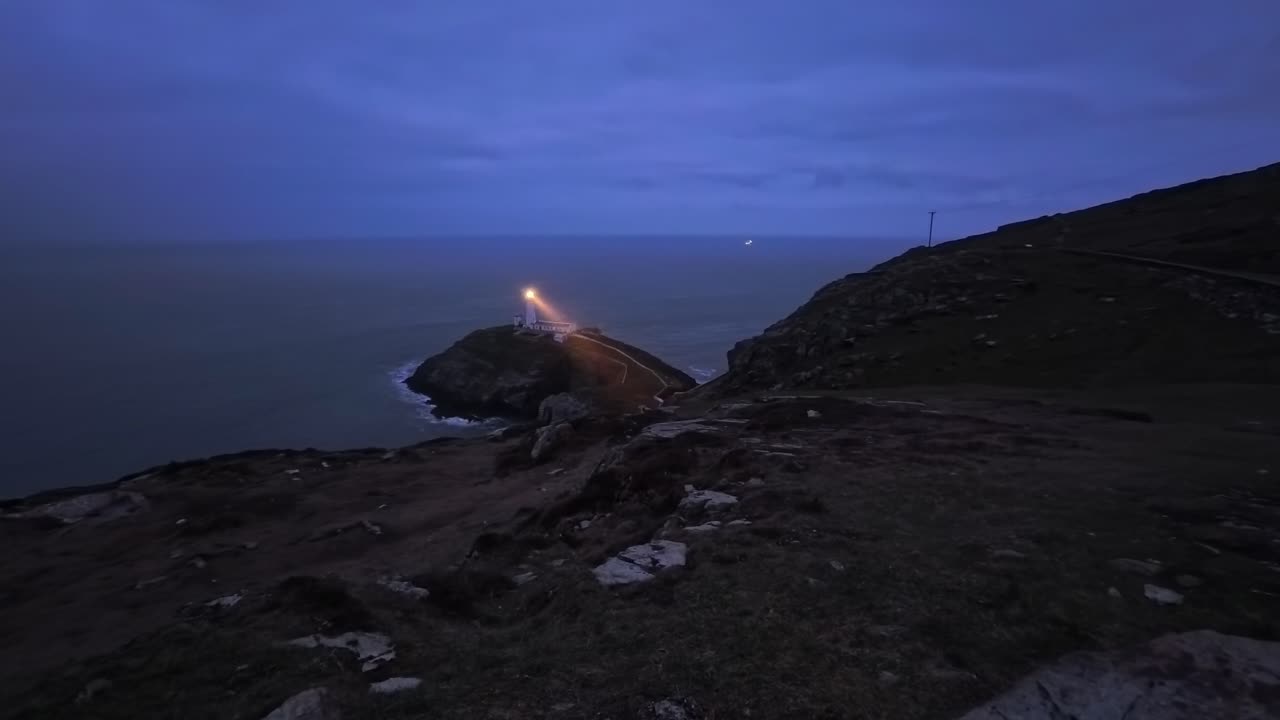 Faro di South Stack: time lapse del fascio di luce rotante della lampada attraverso il Mar d'Irlanda di notte.