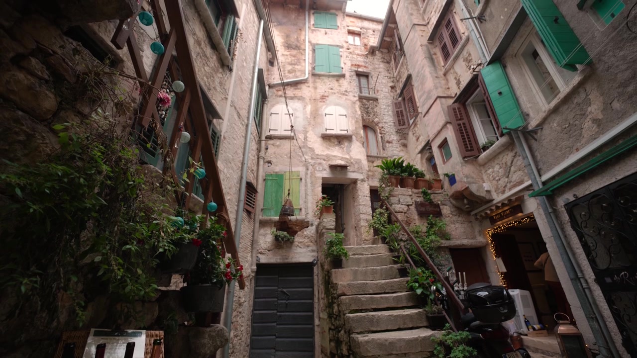 Cortile storico in Croazia con architettura tradizionale, persiane verdi e un'enoteca locale