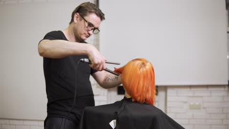 close-up shot of a woman having her hair straightened by a male professional hair stylist in hair salon. shot in 4k