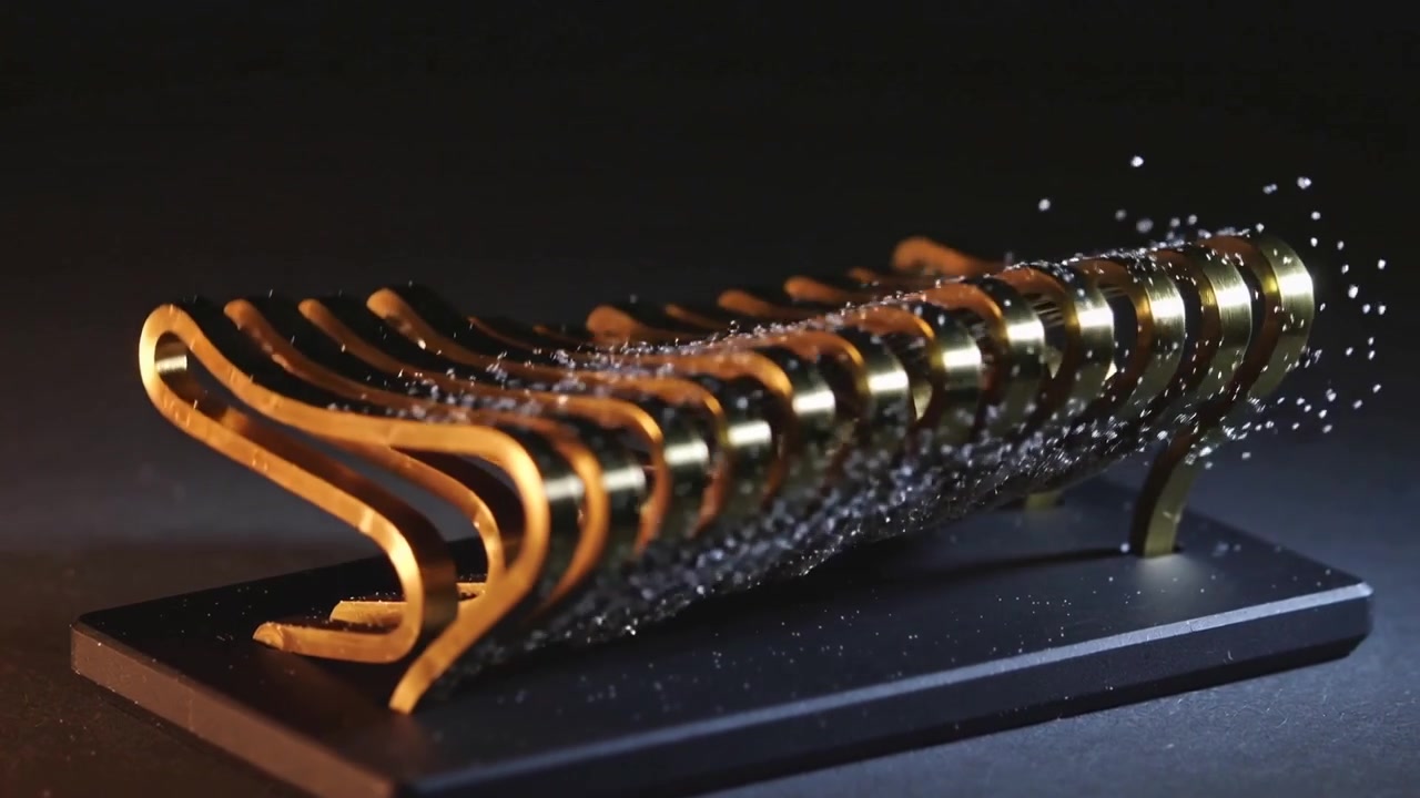 Bande la plus à gauche flexible, boucles d'or segmentées se courbant sur une base noire, dispersant des particules de paillettes