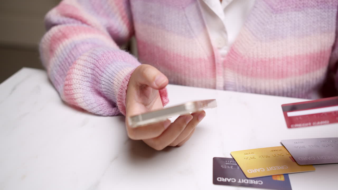 Close-up woman's hand holds a smartphone and selects a mockup Bank credit card for online shopping services to pay money with cashless technology