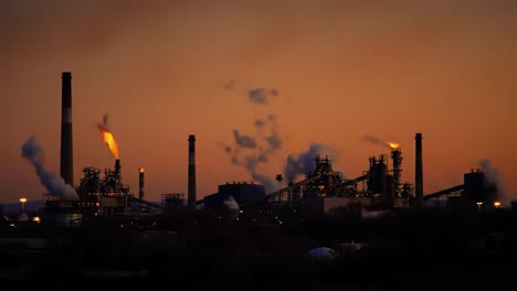 industrial landscapes at dusk: a breathtaking view of smokestacks and emissions against the colorful evening sky, illustrating the complex relationship between industry and environment