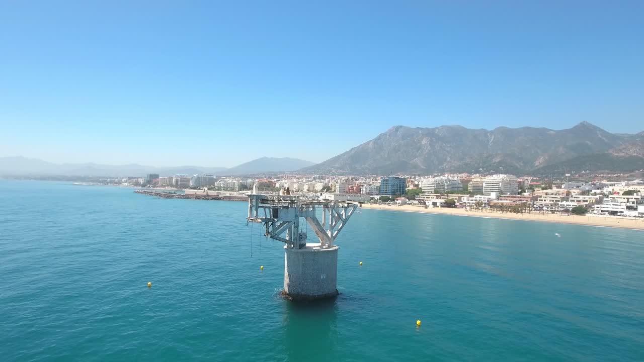 vista aérea de cable beach marbella, gran objeto abandonado en el mar, torre en el mar