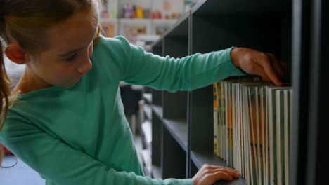 vista frontal de una colegiala caucásica buscando libros en la estantería de la biblioteca de la escuela 4k